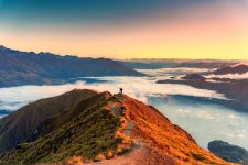 Successful two female hiker enjoying on summit of Roys Peak with sunrise sky amidts Lake Wanaka in autumn at Wanaka, New Zealand
